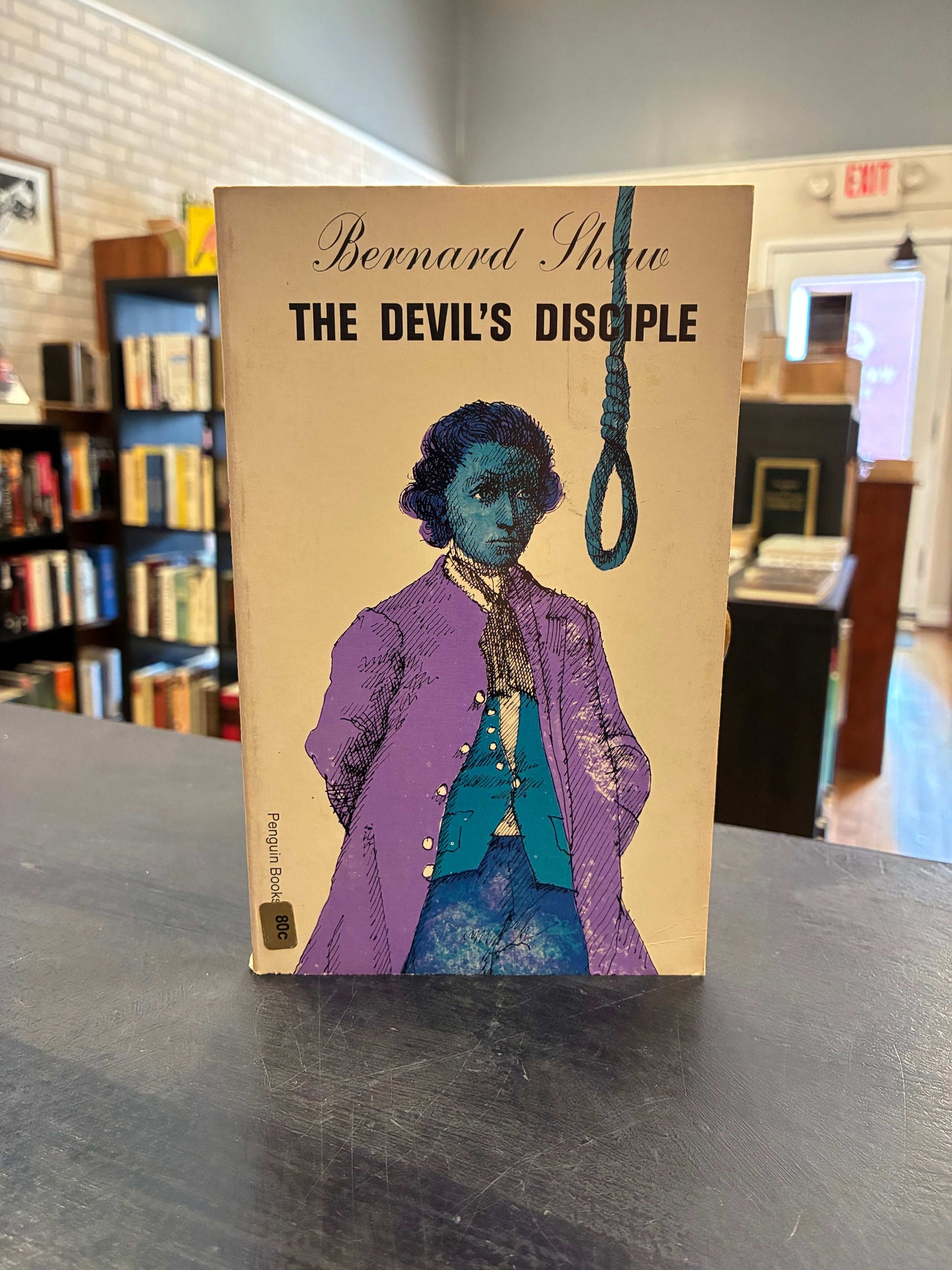 Book titled 'The Devil's Disciple' by Bernard Shaw on a metallic surface with blurred background