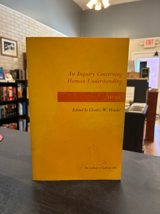 Yellow book titled 'An Inquiry Concerning Human Understanding' by Hume on a surface with a blurred background.