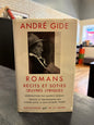 A book titled 'Romans Récits et Soties' by André Gide, published by Éditions de la Pluie, shown on a dark tabletop with a blurred background.
